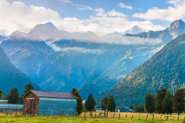 Fototapeta na wymiar Small farmhouse in Fox Glacier Village with mountains on the horizon, New Zealand 