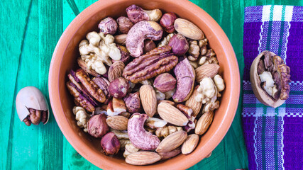 different types of nuts in a brown dish on a wooden background top view	