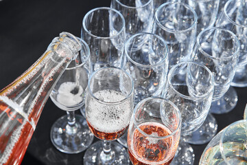 Pink sparkling wine is poured into glasses at a banquet. Top view. Waiter is pouring sparkling wine in flutes