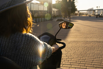 Woman tourist on a four wheel mobility electric scooter on a city street. The woman's face is visible in the rearview mirror © scharfsinn86