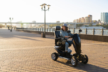 Woman tourist riding a four wheel mobility electric scooter on a city street.  © scharfsinn86