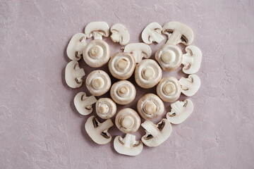 sliced and whole champignons in shape of heart on pink background. High quality photo