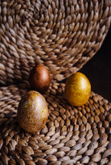 golden eggs on wicker natural background, easter eggs, unusual stylish food design
