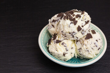 fresh stracciatella ice cream scoops with flakes of dark chocolate in a bowl