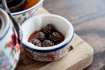 Cones jam in a bowl with Tatar ornament. Served on a wooden tray for a tea party. Delicious jam with baby pine cones in small bowl. Traditional Siberian  dessert - young pine cones jam. 