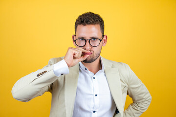 Young handsome businessman wearing suit over isolated yellow background mouth and lips shut as zip with fingers. Secret and silent, taboo talking © Irene