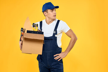 worker with box in hand tools loader yellow background