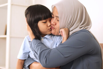 Muslim mother playing with her baby girl, mom and daughter love each other, happy single parent