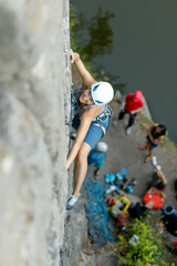 fitness, extreme sport and healthy lifestyle concept - Climber overcomes challenging climbing route. A girl climbs a rock. Woman engaged in extreme sport. Extreme hobby.