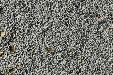 Textures of white pebbles, in between partly other colored stones, wallpaper background