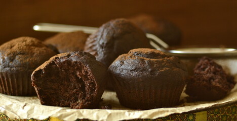 Chocolate banana muffin sprinkled with cocoa on dark background