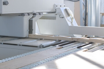 A board for a frame house lies in a woodworking machine. Woodworking industry. Selective focus on the board.