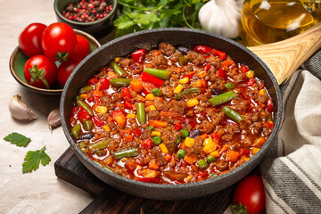 Chili con carne in skillet on light stone table.