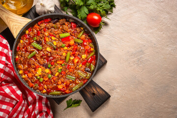 Chili con carne in skillet on dark stone table.