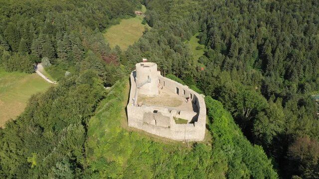 Flying around medieval castle on top of mountain in middle of forest. Village Rytro, Poland.