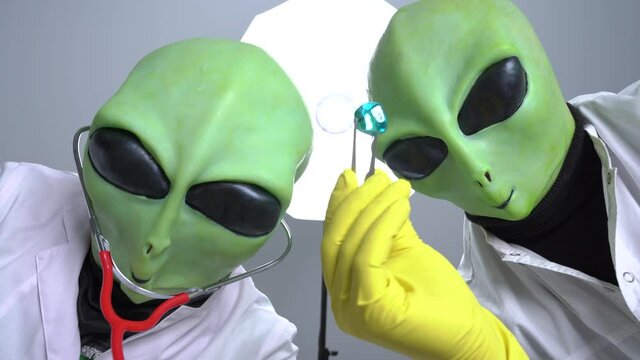 Humanoids robbed someone to conduct experiments on them and torture. One uses stethoscope, other holds crystal stone with tweezers. View through eyes of victim.