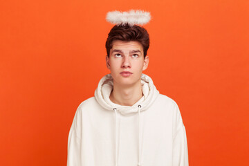 Surprised young man in casual white sweatshirt with hood looking at halo over his head, charity,...