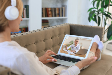 Middle aged woman making video call with her doctor during self isolation and quarantine. Online consultation. Patient in video conferencing with general practitioner on laptop.