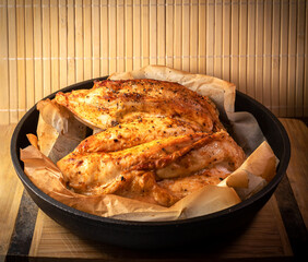 A roasted chicken breast in a cast-iron pan by rustical style.