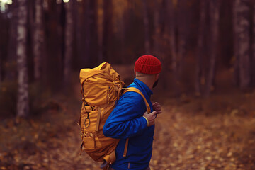 man with  backpack a view from the back, hiking in the forest, autumn landscape, the back of  tourist with a backpack