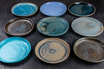 Close-up abstract background with decorative empty round ceramic dishes of different colors. Plates in the pottery workshop, concept of handwork