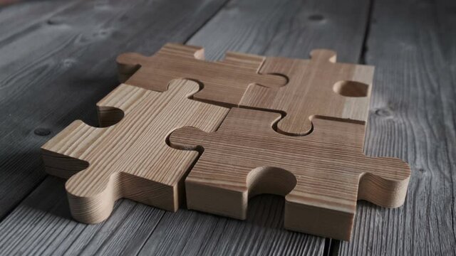 Business people assembling wooden puzzle on work table, teamwork concept