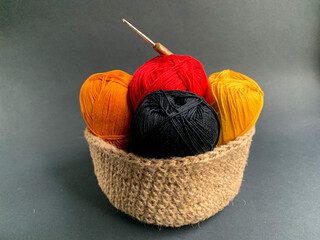 Yarn in a knitted basket on a black background. Yarn of different colors. The concept of creating a product. Crafts, Hobbies, creating products with your own hands. Crocheting and knitting.