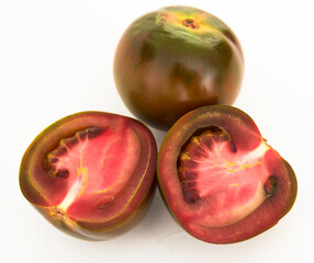 black tomatoes and two halves on white background