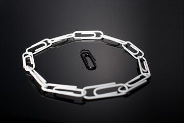 A circle of paperclips with one in the middle that is not fitting in and is surrounded by the...