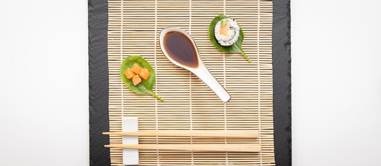 Présentation de plat de cuisine Japonaise, dés de saumon, sushi et maki sur fond noir avec sauce soja.	