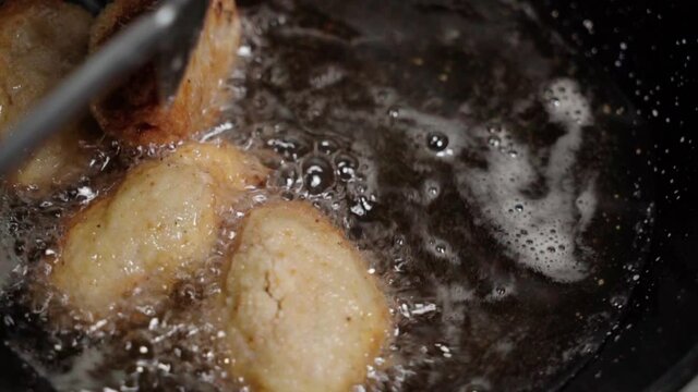 Turning Spanish croquettes frying in oil with spatula, Slowmo Closeup