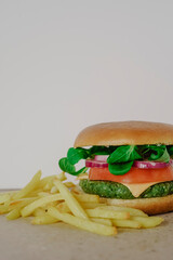 Healthy vegan spinach, tomato, arugula, onion and cheese green burger with potatoes 