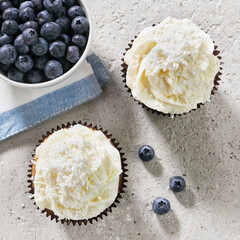 blueberry cupcake, muffin, with cream and coconut flakes on gray concrete background