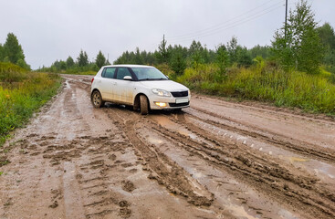 Fototapeta na wymiar passenger white hatchback stuck on the road in rainy weather on a country road. blurry focus