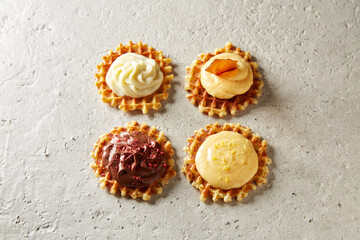 Belgian waffles with different fillings and creams on a light concrete background