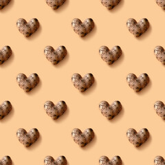 Seamless pattern of abnormal potato in shape of heart on beige background.