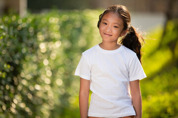 Portrait of smiling Asian kid girl in white tshirt in garden