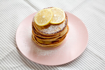 Homemade Lemon Ricotta Pancakes on a pink plate, side view. Close-up.