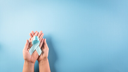 World diabetes day concept. Hand holding blue ribbon, symbolic bow color raising awareness in...