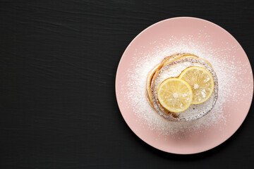Homemade Lemon Ricotta Pancakes on a pink plate on a black background, top view. Flat lay, overhead, from above. Copy space.
