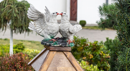 Wooden figurine of two beautiful white doves kissing together in the garden