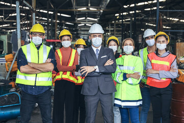 Leader or manager meeting with engineer and technician or operator while posing in factory workplace, team working at maintenance machine shop, face mask covid-19 protection