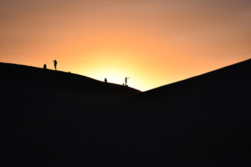 Silhouette of some dunes in the desert at sunset.