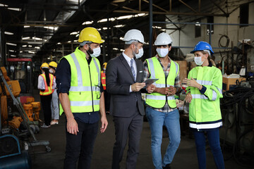 Leader or manager using tablet and meeting with engineer and technician while line walk in factory workplace, team wear face mask whine working at maintenance machine shop 