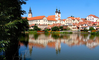 View of Telc town across the lake with reflections of the buildings in the water