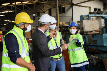 Leader or manager using tablet and meeting with engineer and technician while line walk in factory workplace, team wear face mask whine working at maintenance machine shop 