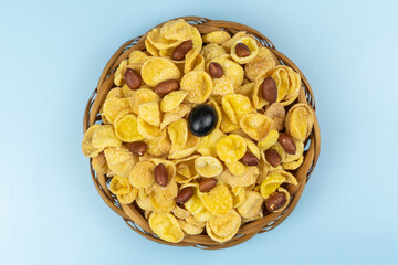 Cornflakes with nuts and grapes in a brown wicker plate close up