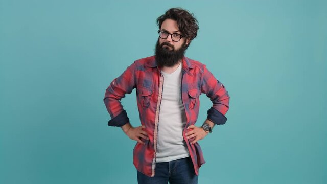 Young bearded man annoyed with bad attitude making stop sign with hand, saying no, expressing security over turquoise background.