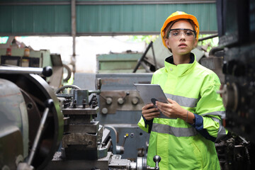 A Engineer woman using tablet or computer for inspect or checking or adjust or operate control the machine in workshop factory, the technician repair or maintenance part or equipment 