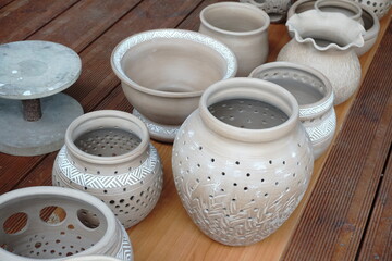 handmade unbacked crockery and pots on the table in the potter's studio. clay before firing in a...